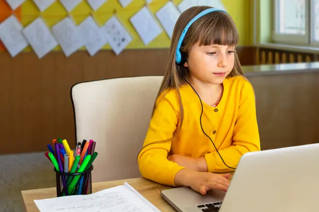 Elementary student at school participating in online tutoring programs for reading competency
