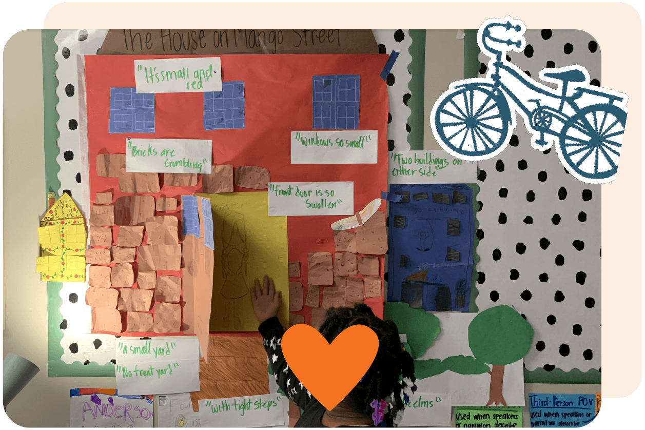 Child interacting with a colorful classroom poster titled "The House on Mango Street," featuring various educational notes and cutouts depicting buildings. A bicycle doodle and orange heart adorn the frame.