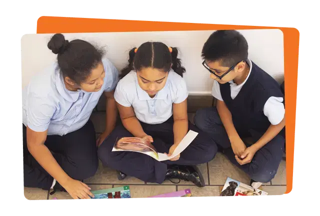 Three children sitting on the floor, reading a book together.