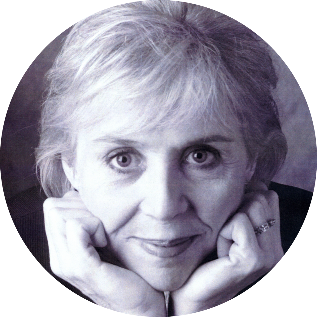 A grayscale portrait of an older woman with light hair, resting her chin on her hands and looking directly at the camera.