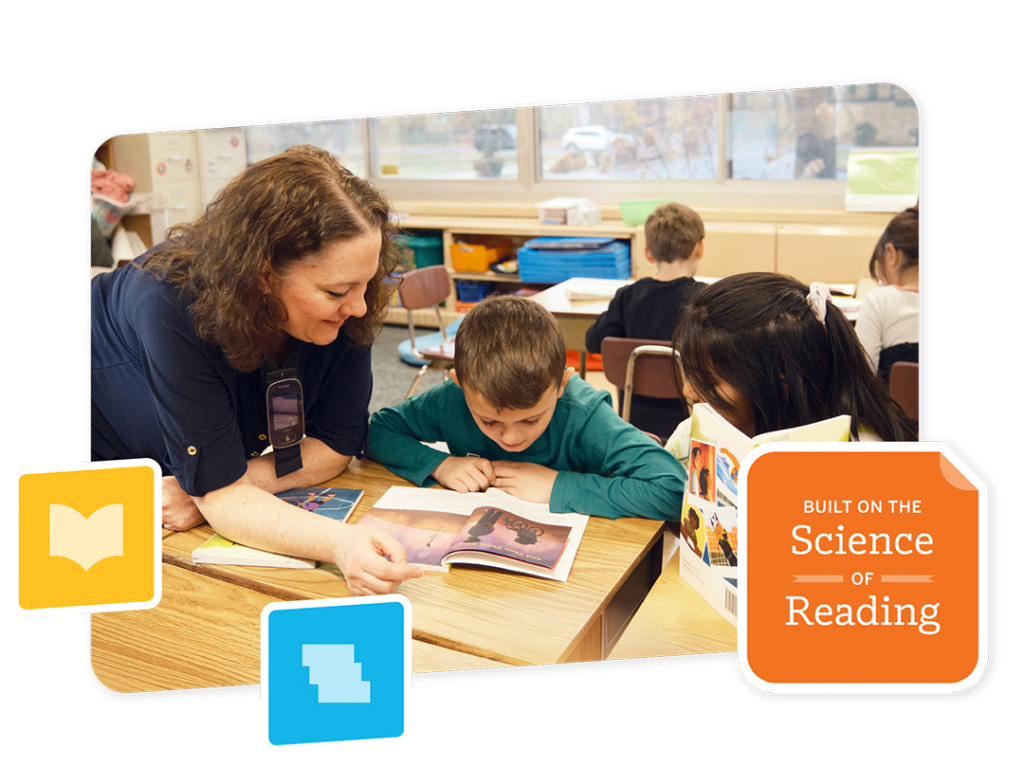 A teacher, equipped with science of reading training, leans over to assist two young students reading a book at a classroom table, with other children working in the background.