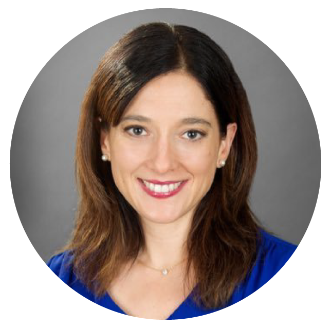 A woman with shoulder-length brown hair, wearing a blue top, smiles at the camera against a gray background.