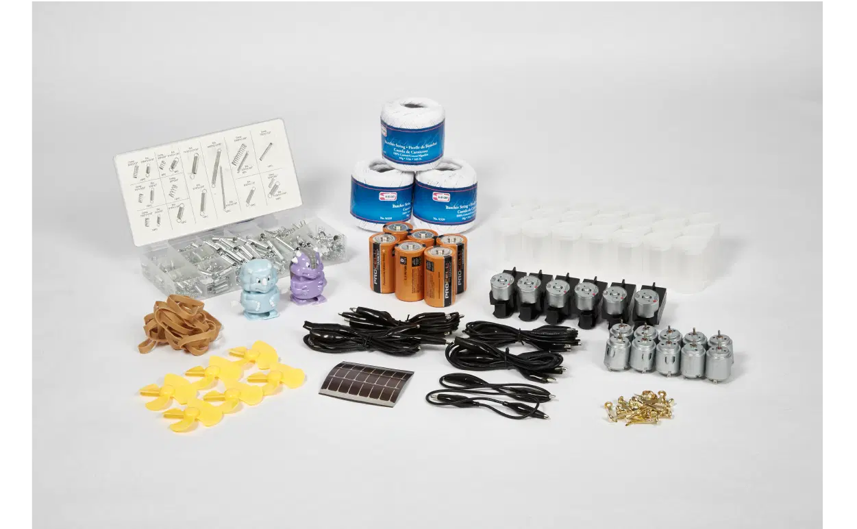 A collection of assorted electronic components and supplies, including batteries, motors, wires, switches, rubber bands, small propellers, cups, solar panel, bulbs, and fasteners.