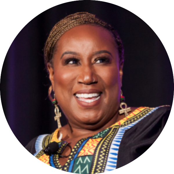 A person smiling and wearing patterned clothing with colorful designs and a microphone headset.