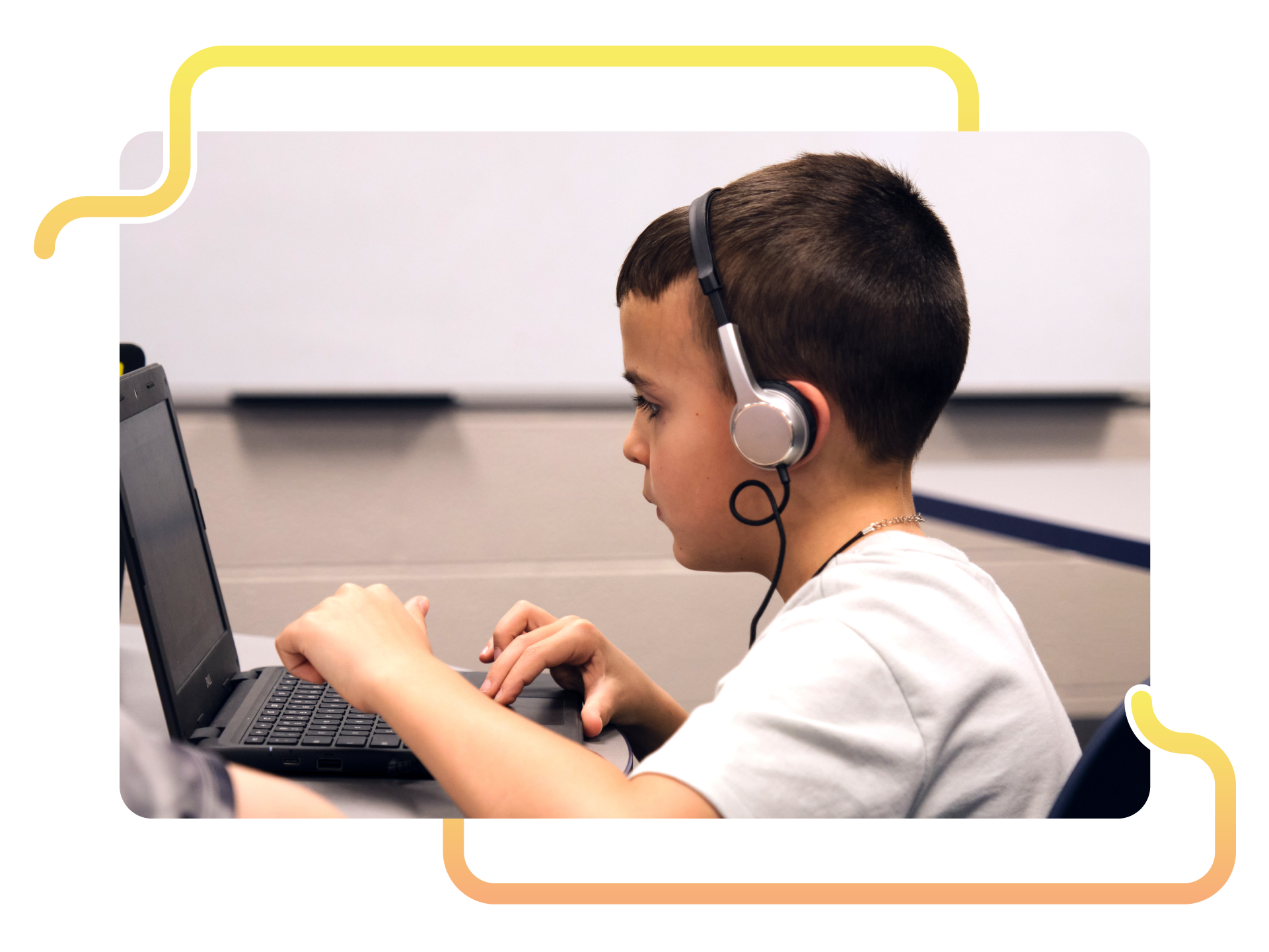 A boy wearing headphones sits at a desk, focusing intently on his laptop as he completes a math assessment in a classroom setting.